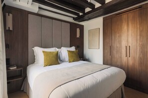 A bedroom with a large bed, wooden wardrobe, and a nightstand.