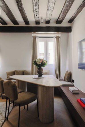 A dining area with a wooden table, chairs, a vase with flowers, and a bench with cushions. - AC Apartment 2br/6p - Notre-dame de Paris (Paris)