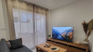 Una sala de estar moderna con un sofá, una mesa de centro, un televisor y un ventanal corredizo.