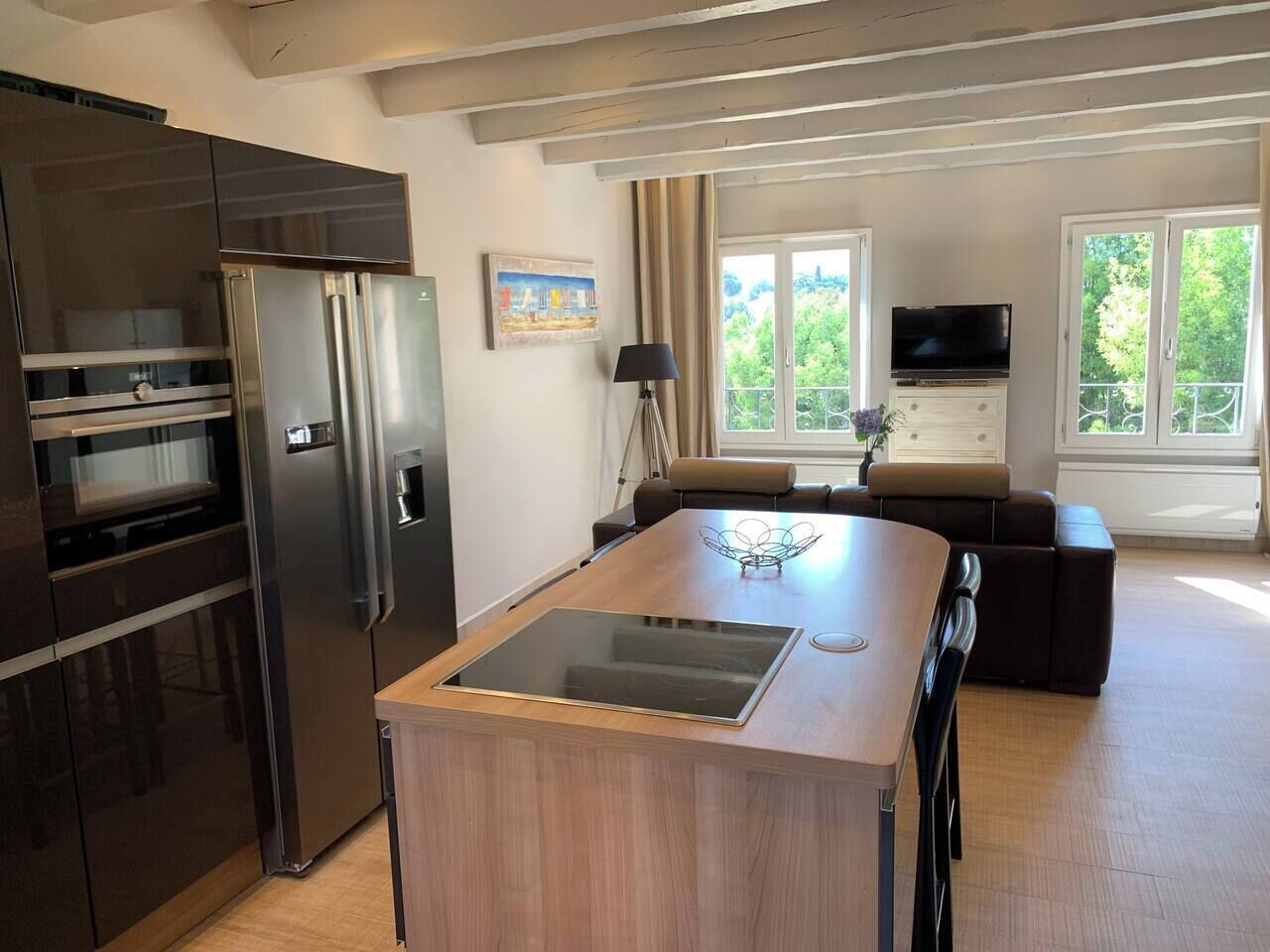 Cozinha moderna com ilha central, forno embutido e uma geladeira grande.