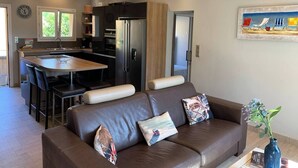 A modern kitchen with a central island, a dining area with a brown leather sofa, and a painting on the wall.