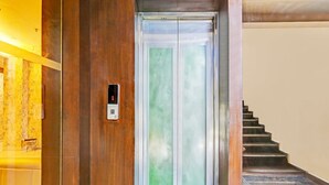 Un ascenseur doté d’un écran numérique affichant le chiffre 1, un mur en bois et un escalier.