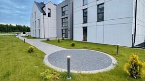 Ein modernes Gebäude mit flachem Dach, zahlreichen Fenstern und einer gepflasterten Fläche mit einem runden Garten.
