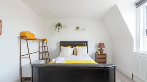 A bedroom with a bed, a ladder, a nightstand, a lamp, and a window. - Apt - Stay 6 - Paid Parking - Petsok - Stratford (London)