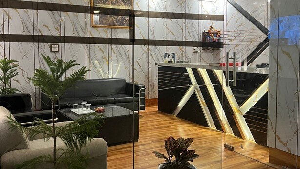 Een modern interieur met een receptiebalie, een zithoek en een trap.