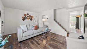 A living room with a grey sofa, a small table, and a staircase leading to another area. - The StayBerry - Stay for 6 (Columbus)
