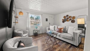 A modern living room with a grey sofa, a small coffee table, and a TV mounted on the wall. - The StayBerry - Stay for 6 (Columbus)