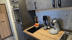 A modern kitchen with a built-in oven, a microwave, a sink, and a coffee maker. - Ochsenkopf apartment (Bischofsgrün)