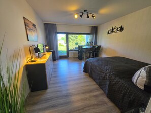 A bedroom with a bed, desk, chair, and a view of the outdoors. - Ochsenkopf apartment (Bischofsgrün)