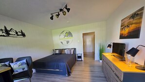 A modern bedroom with a bed, desk, chair, and a painting on the wall. - Ochsenkopf apartment (Bischofsgrün)