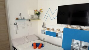 Ein Hotelzimmer mit Bett, Wandfernseher, einer Ablage mit Dekoration und Telefon an der Wand.