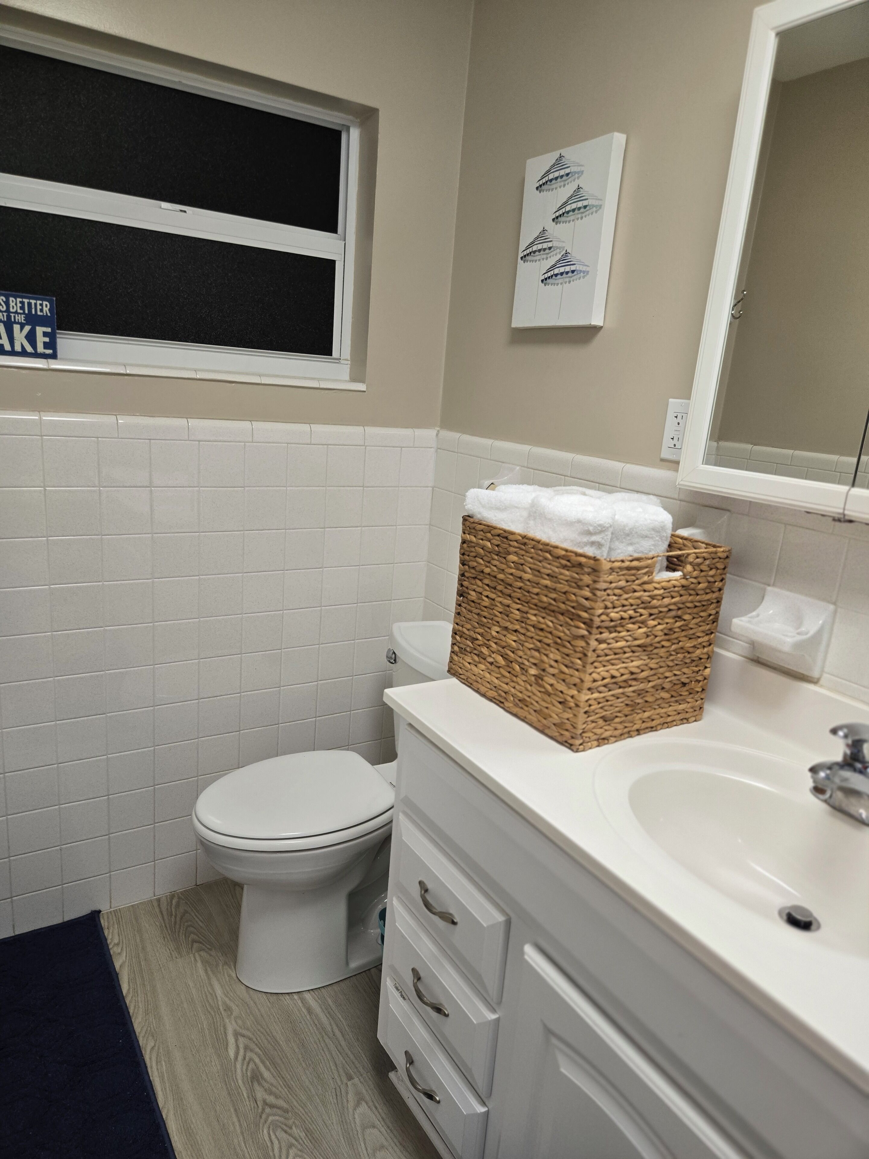 Un baño con inodoro, lavabo, espejo y ventana.