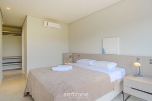 A hotel room with a bed, bedside table, lamp, and an air conditioning unit. - Modern House With Pool Next to Surfland Roi00 (Garopaba)