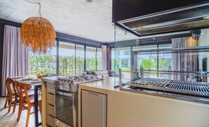 A modern kitchen with a large island, stainless steel appliances, and a view of greenery outside. - Modern House With Pool Next to Surfland Roi00 (Garopaba)