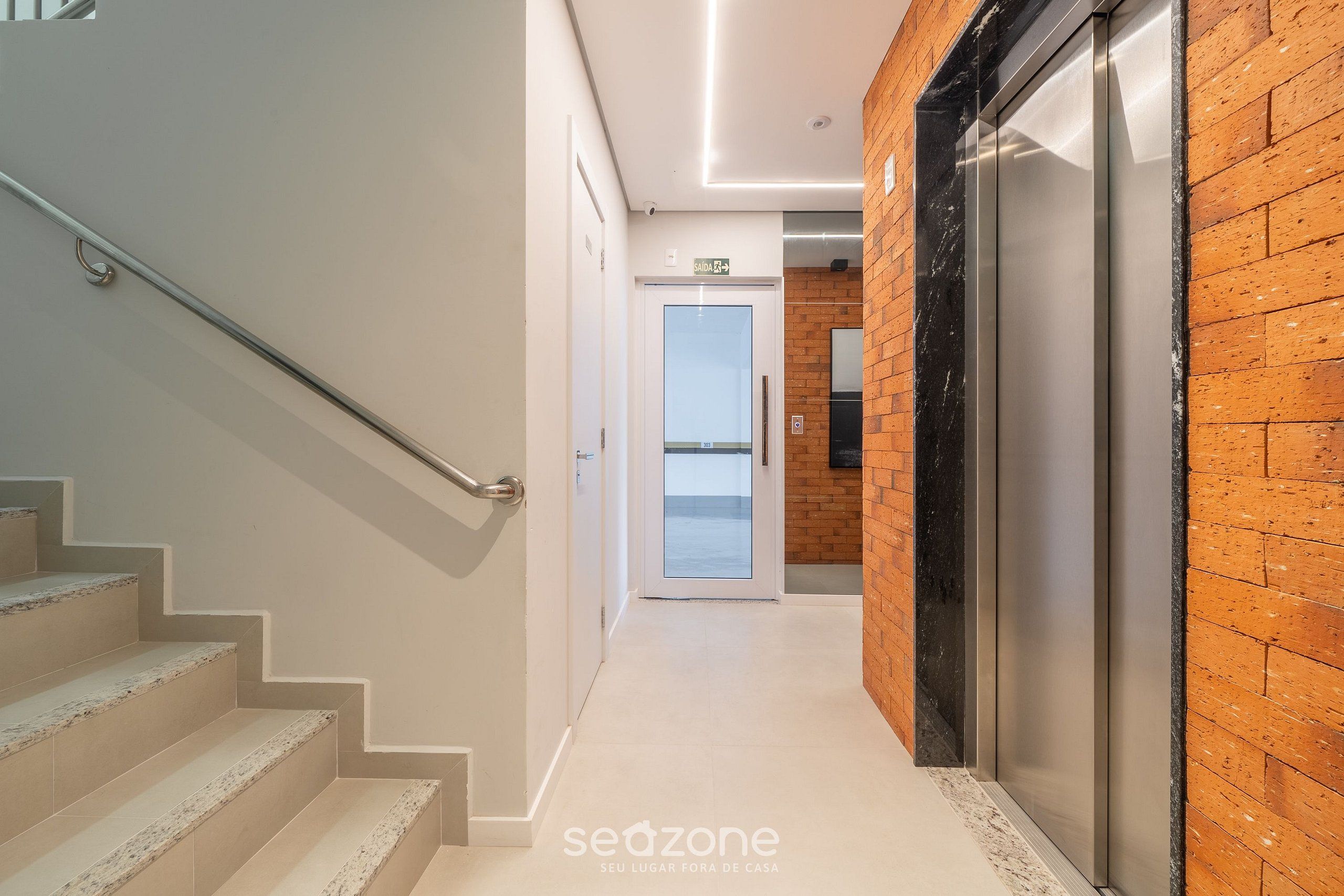 Een modern interieur met een trap, lift en een uitzicht door een glazen deur.