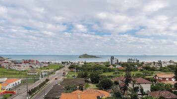 Uma cidade costeira com edifícios residenciais e comerciais, céu claro e vista para o mar.
