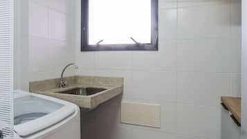A small bathroom with a sink, a window, and a ventilation grille.