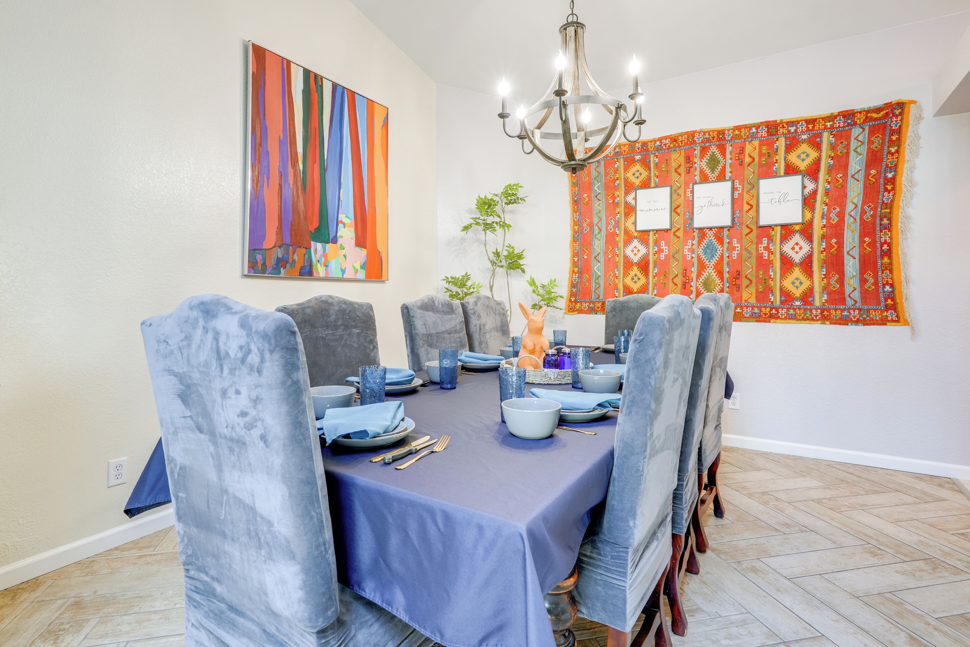 A dining room with a blue tablecloth, grey chairs, and a chandelier.