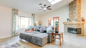 Ein Wohnzimmer mit einem Ecksofa, einem Kamin und einem Deckenventilator.