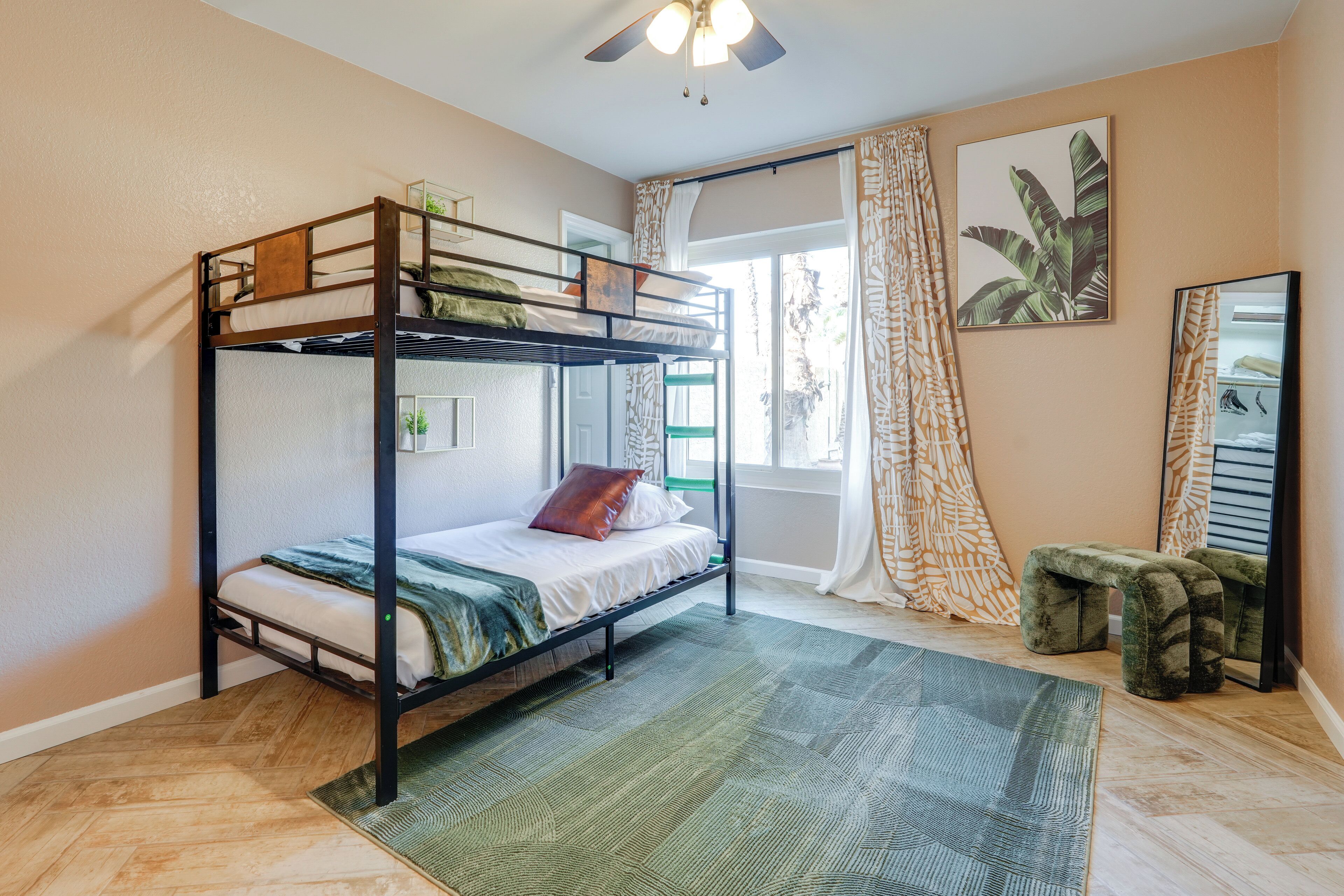 Camera con letto a castello, una finestra, uno specchio e un tappeto verde.
