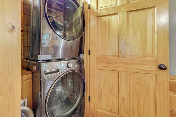 A laundry room with two stacked washing machines and a wooden door. - 1 Mi to Dtwn Gatlinburg: Hot Tub Haven in Smokies! (Gatlinburg)