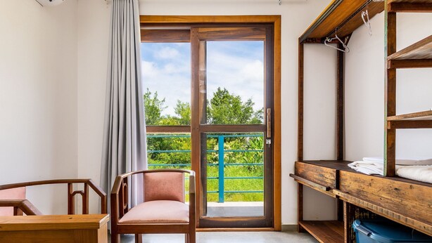 A room with a wooden chair, a small table, a blue storage bin, and a wooden shelf with towels. - 3BR House w/ BBQ 800m From Beach Rju8301 (Bombinhas)