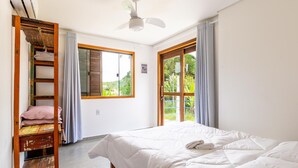 A bedroom with a bed, a window, a ceiling fan, and a wooden shelf with towels. - 3BR House w/ BBQ 800m From Beach Rju8301 (Bombinhas)