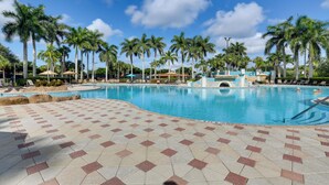 A swimming pool with palm trees and lounge chairs.