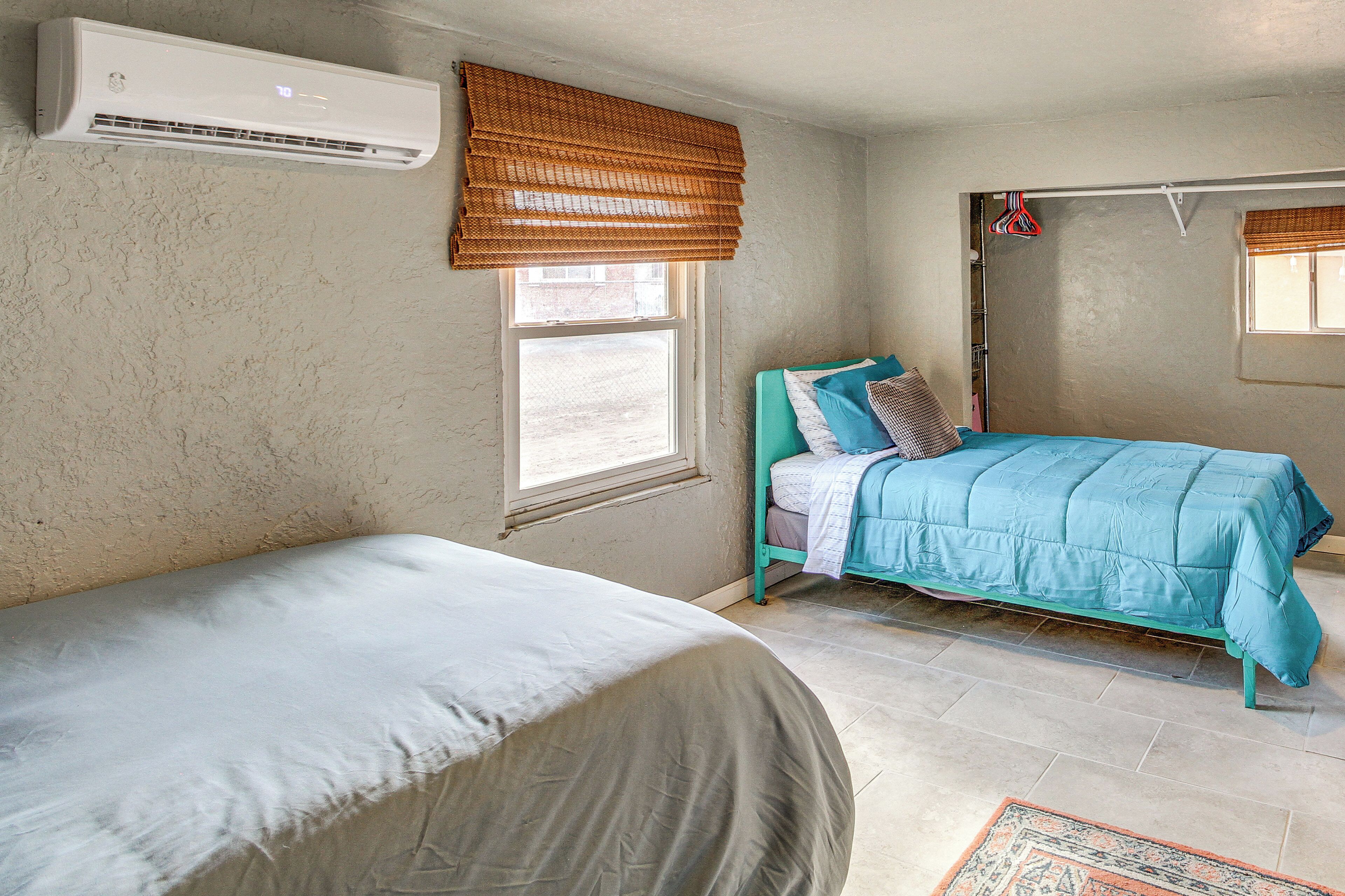 Ein Schlafzimmer mit zwei Betten, einem Fenster mit Jalousie, einer Klimaanlage und einem kleinen Teppich.