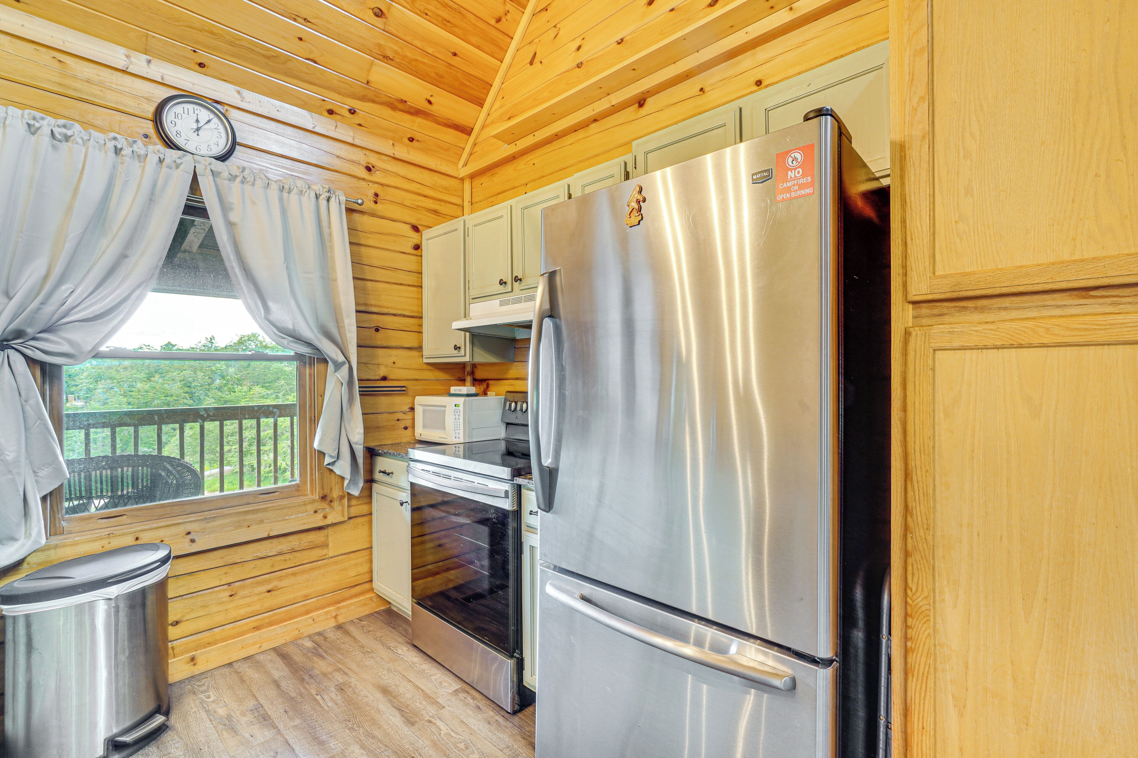 Une cuisine rustique aménagée dans une cabane en bois, avec un réfrigérateur, un four et un four à micro-ondes en acier inoxydable.