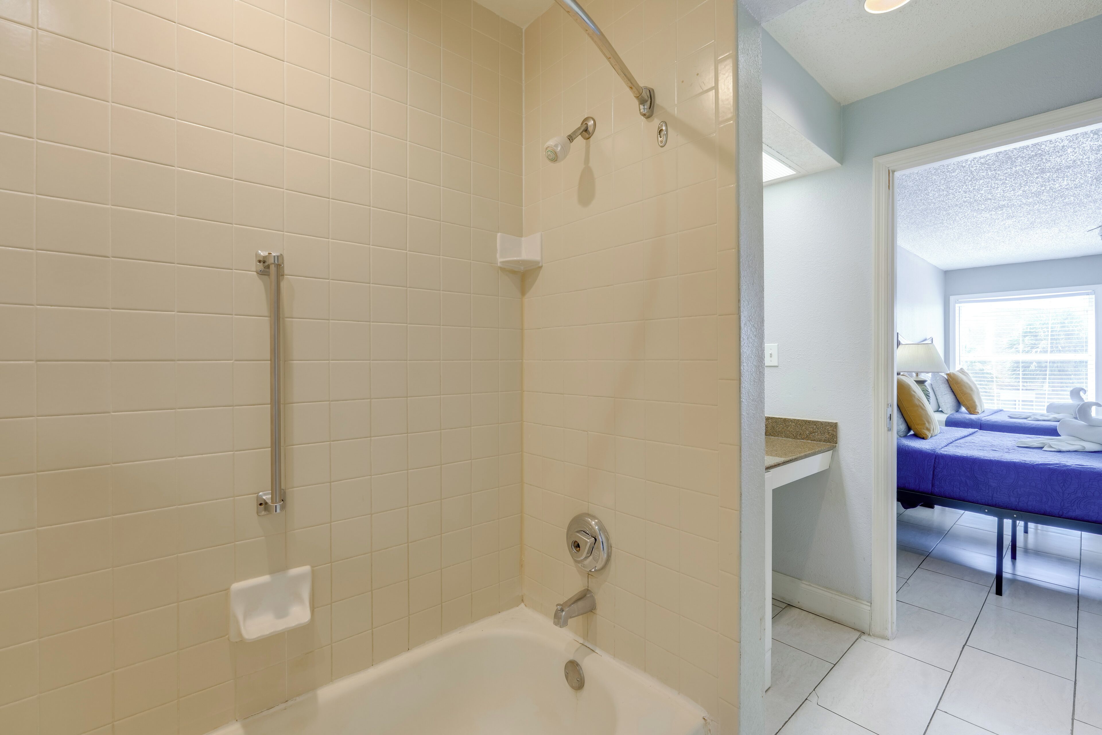 A bathroom with a bathtub, a shower with a grab bar, and a toilet.