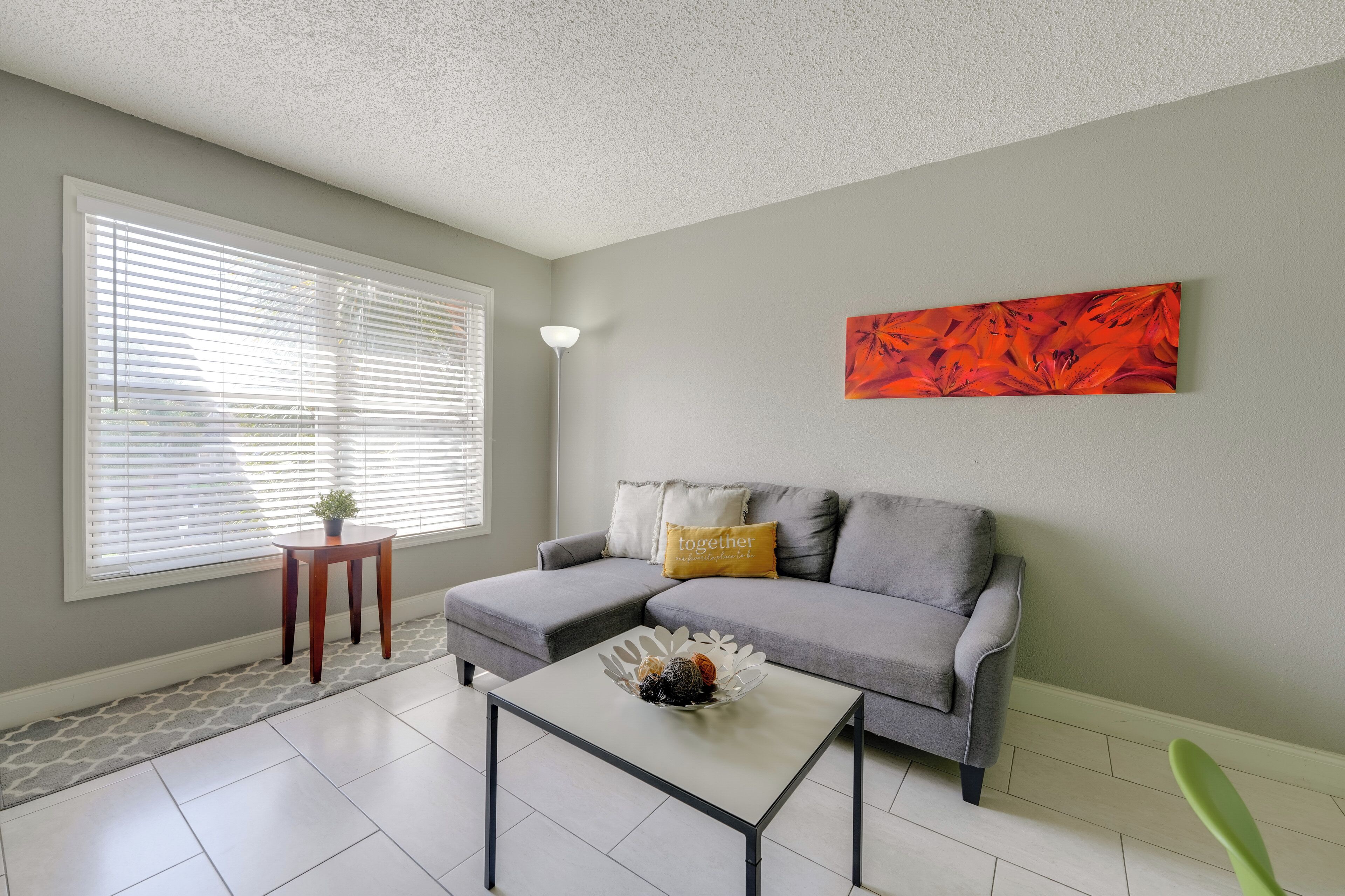 A living room with a grey sofa, a white coffee table, and a painting on the wall.