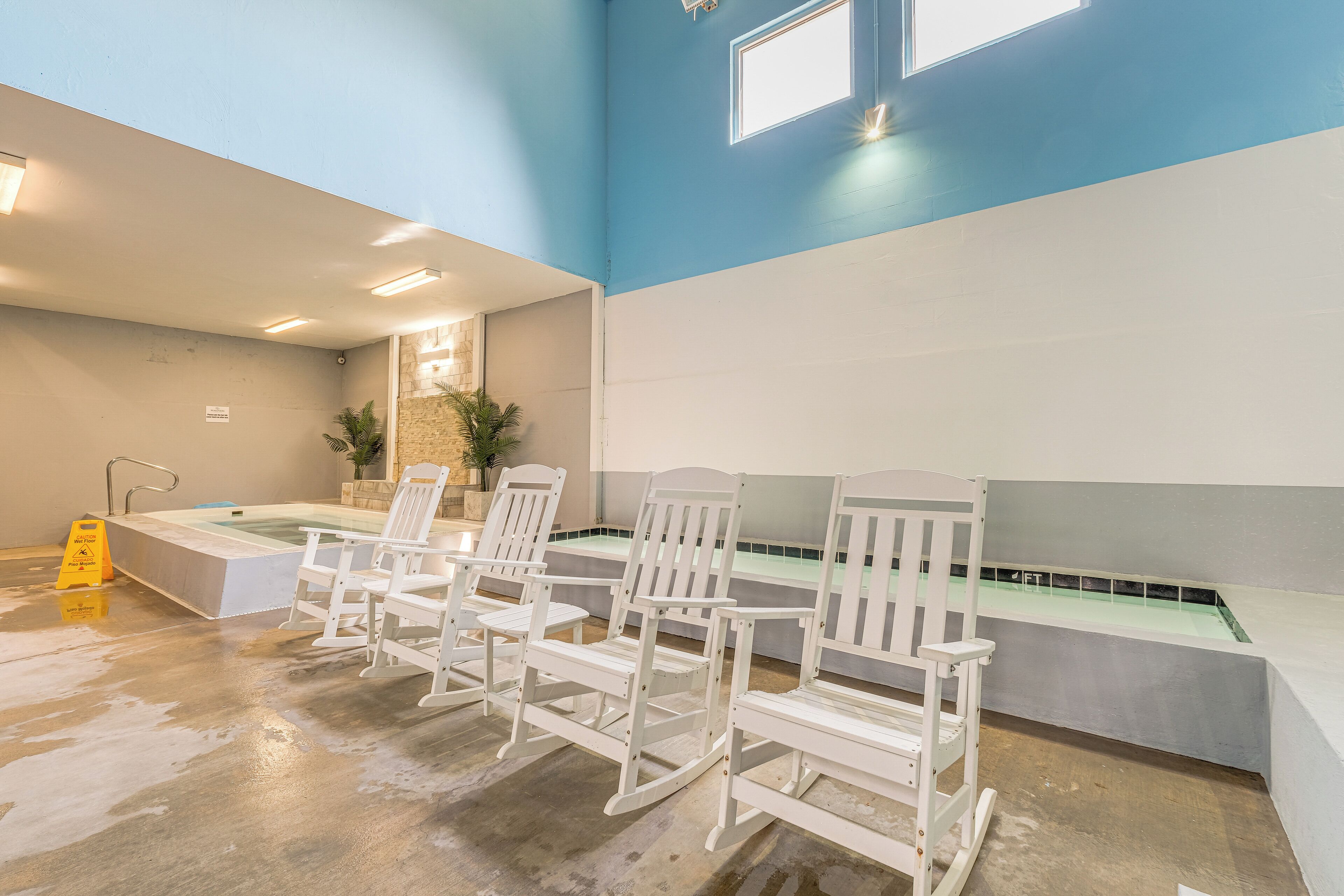 A spa area with a hot tub, white rocking chairs, and a blue and white wall.