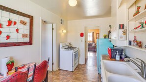 A kitchen with a stove, sink, and a dining area with chairs and a table.