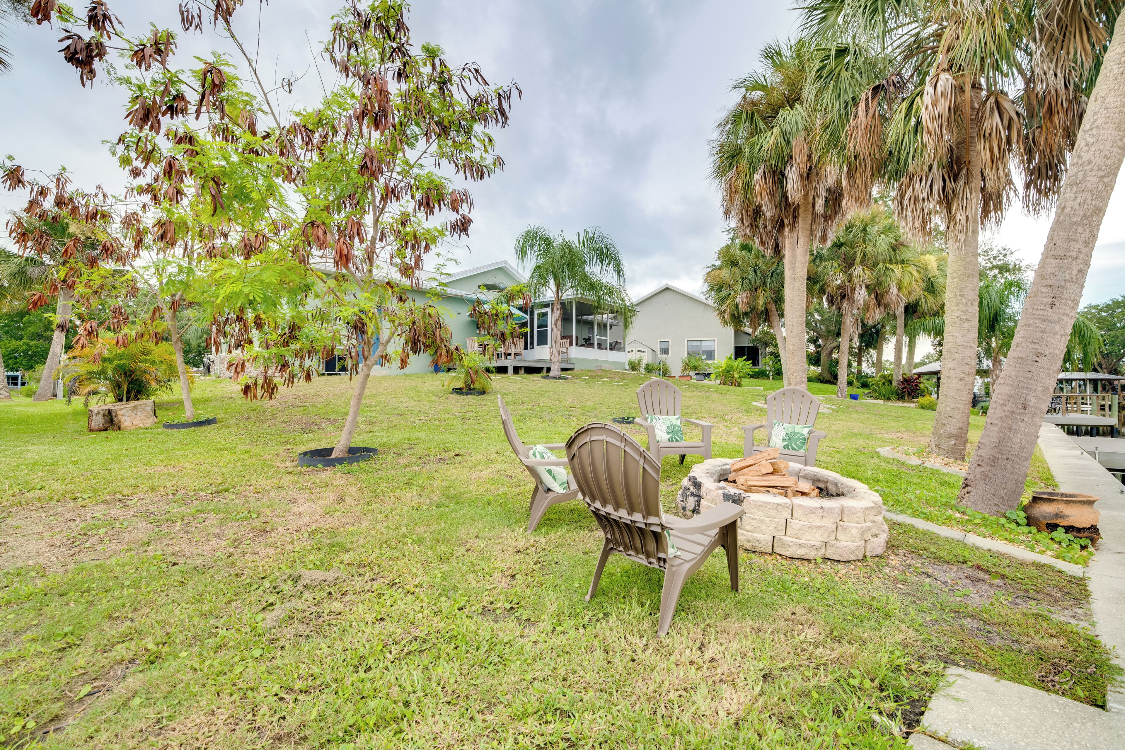 A grassy outdoor area with a fire pit, chairs, and a small table.