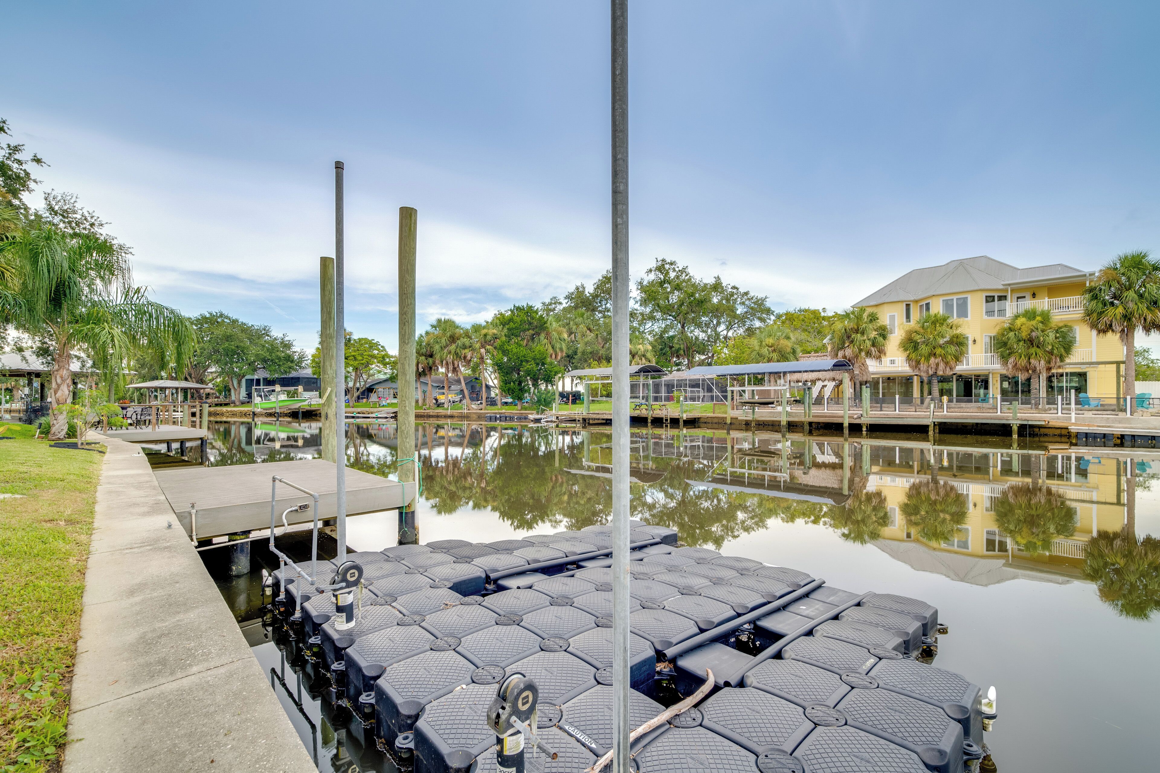 A waterfront dock with hexagonal platforms, a clear sky, and a building with a balcony in the background.