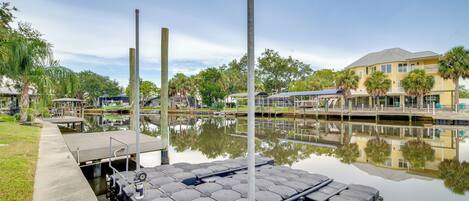 A waterfront dock with hexagonal platforms, a clear sky, and a building with a balcony in the background.