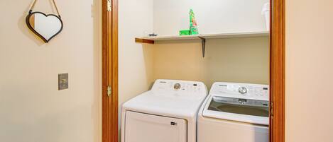 A laundry area with two white washing machines, a heart-shaped decoration on the wall, and a small shelf with a green item.