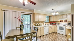 A kitchen with wooden cabinets, a dining table, and a ceiling fan. - 1/2 Mi to Desoto Lake: Hot Springs Village Home (Hot Springs Village)