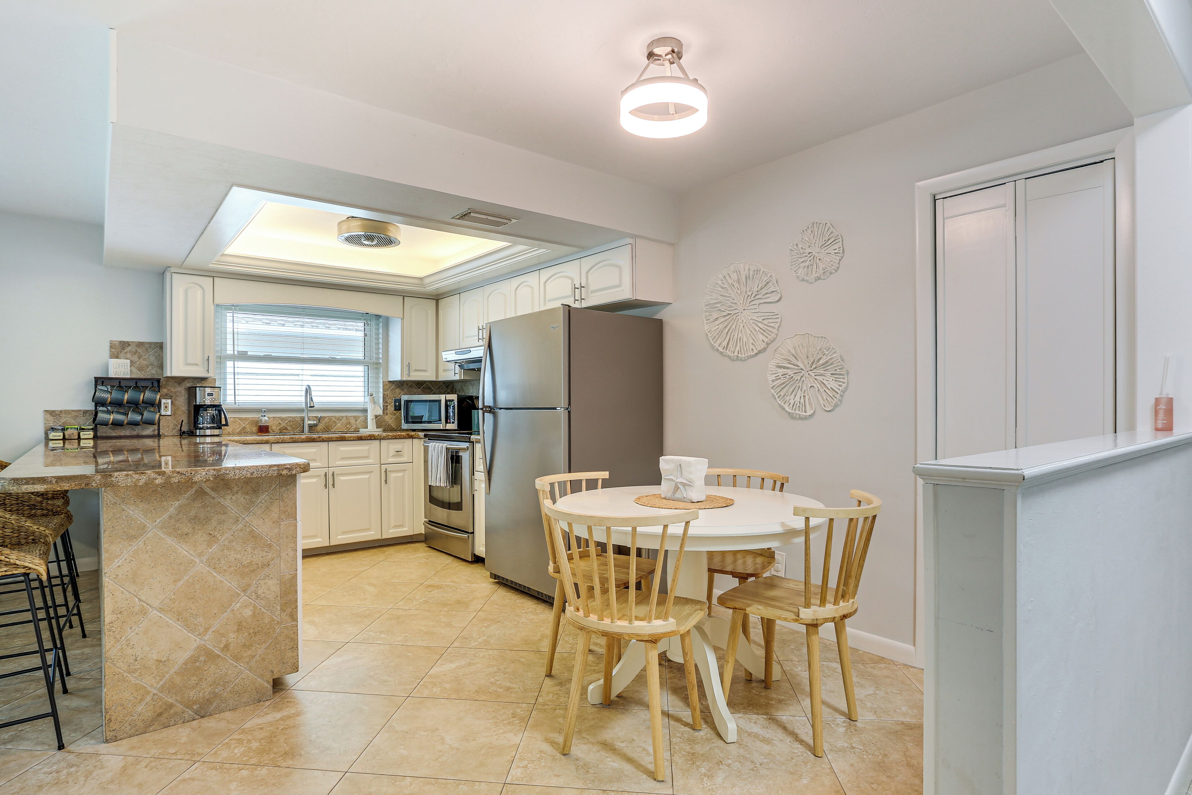A modern kitchen with a central island, dining table, and chairs.