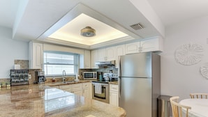 Cozinha moderna com bancadas de granito, eletrodomésticos de aço inoxidável e uma ilha central.
