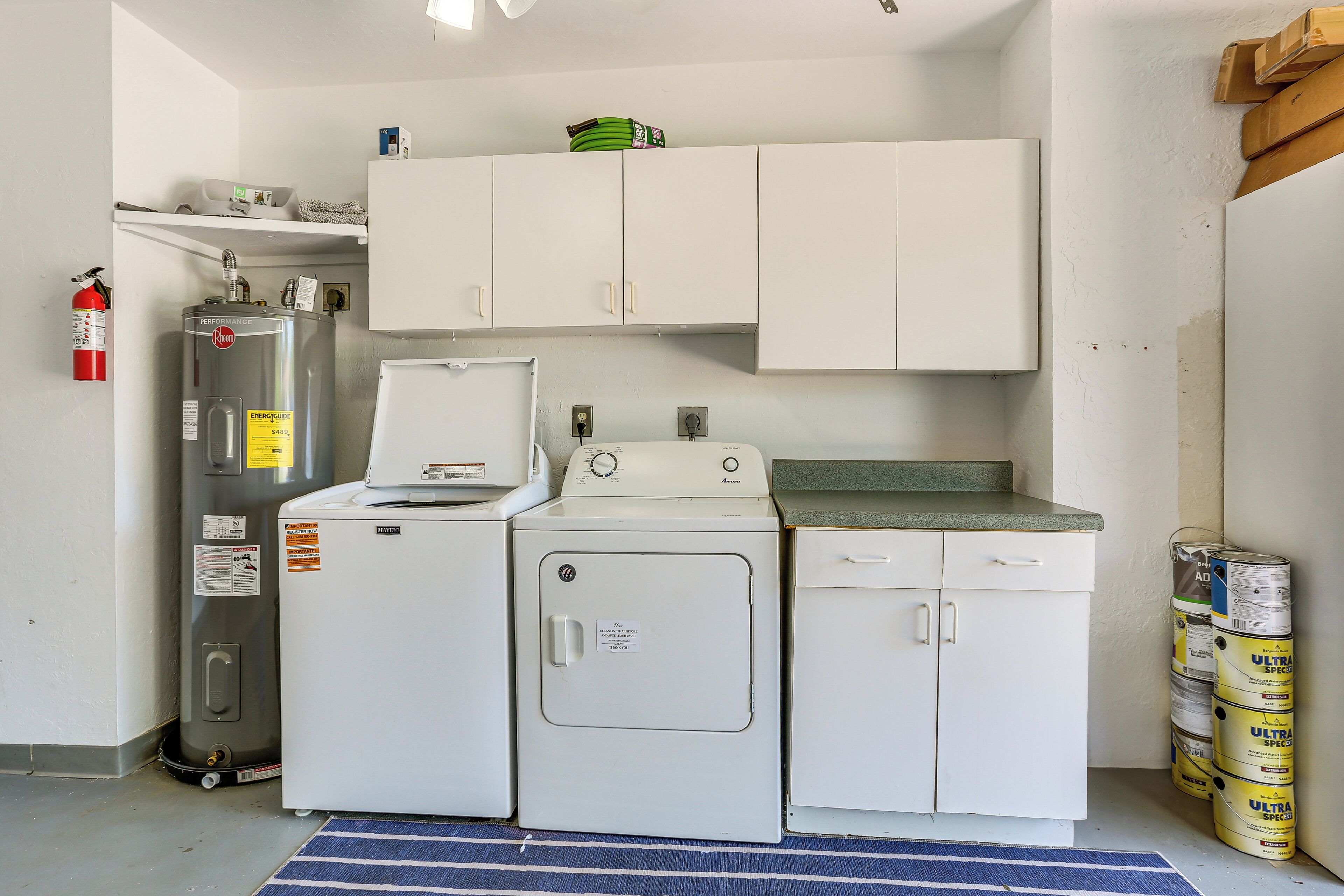 Een kleine keuken met een koelkast, wasmachine, droger en kastjes.