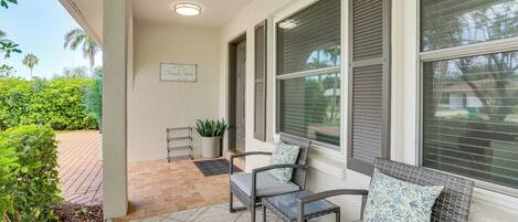 A covered outdoor seating area with wicker furniture and a welcome sign.