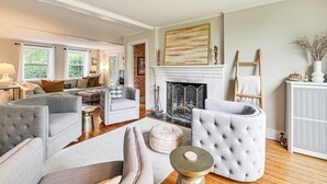 A spacious living room with a fireplace, comfortable seating, and large windows.