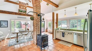 A kitchen with a brick stove, white cabinets, and a view of the outdoors.