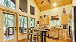 A spacious kitchen with wooden cabinets, a stainless steel refrigerator, and a dining area with a table and chairs. - Hot Tub & Game Room: Ronald Retreat 2 Mi to Lake! (Cle Elum)