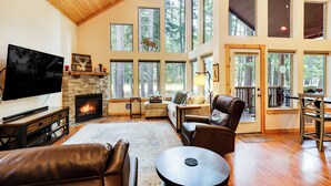 A spacious living room with a fireplace, large windows, and a television. - Hot Tub & Game Room: Ronald Retreat 2 Mi to Lake! (Cle Elum)