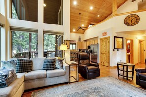 A spacious living room with a sofa, armchairs, and a rug. A kitchen is visible in the background with wooden cabinets and a refrigerator. - Hot Tub & Game Room: Ronald Retreat 2 Mi to Lake! (Cle Elum)