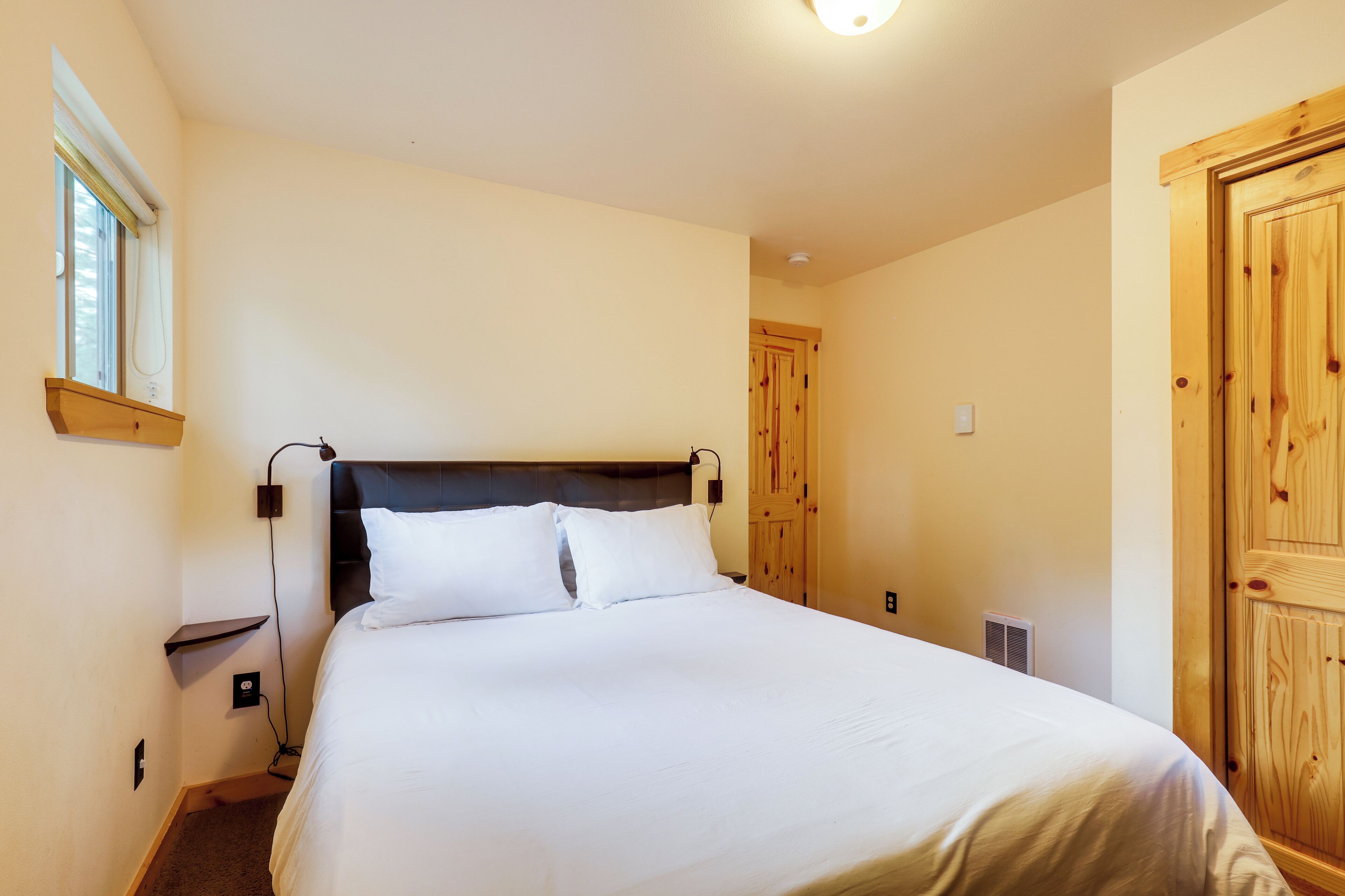 Une chambre avec un grand lit, une armoire en bois, une table de chevet et une fenêtre.