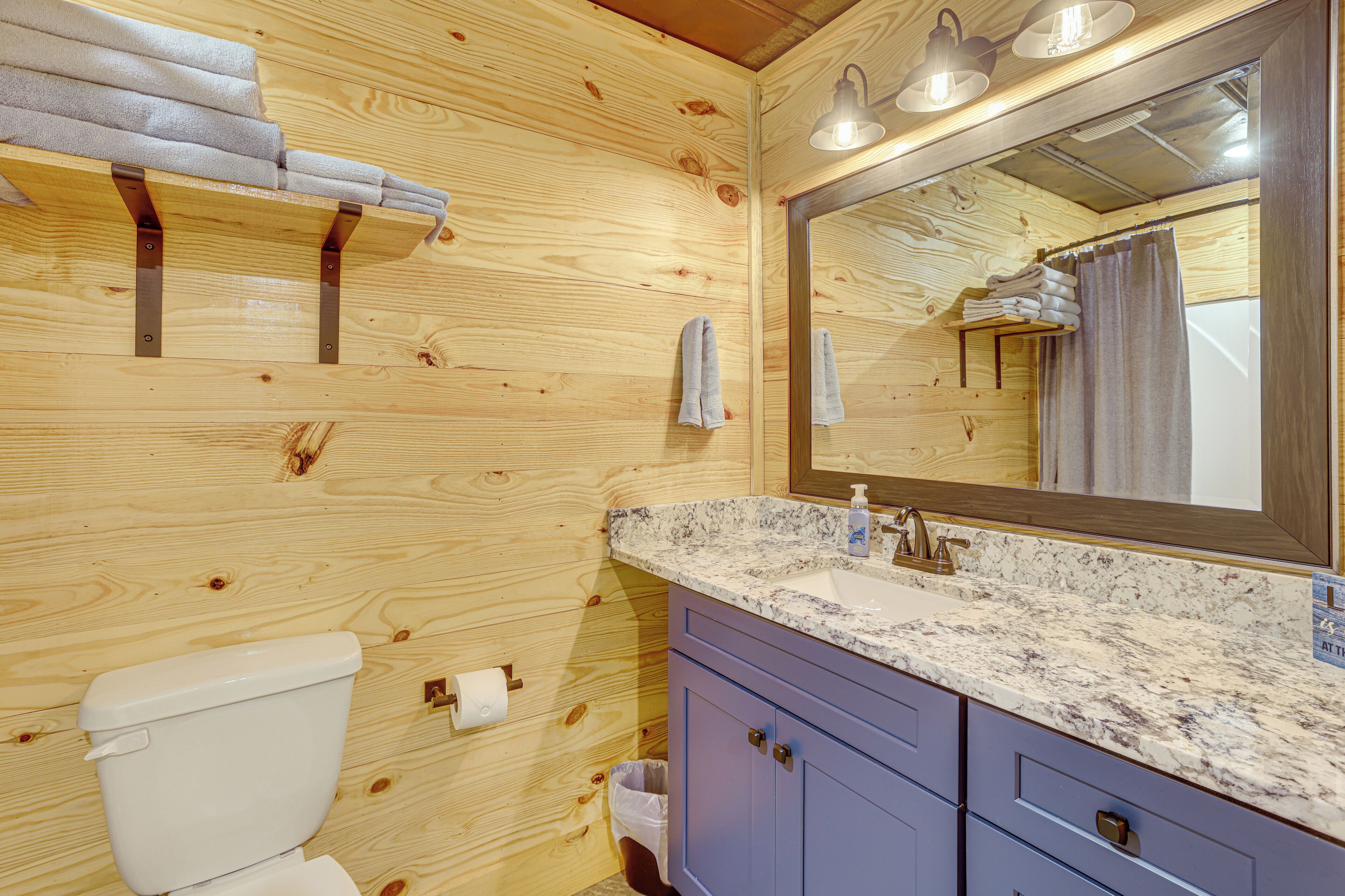A wooden-paneled bathroom with a sink, mirror, and towels.